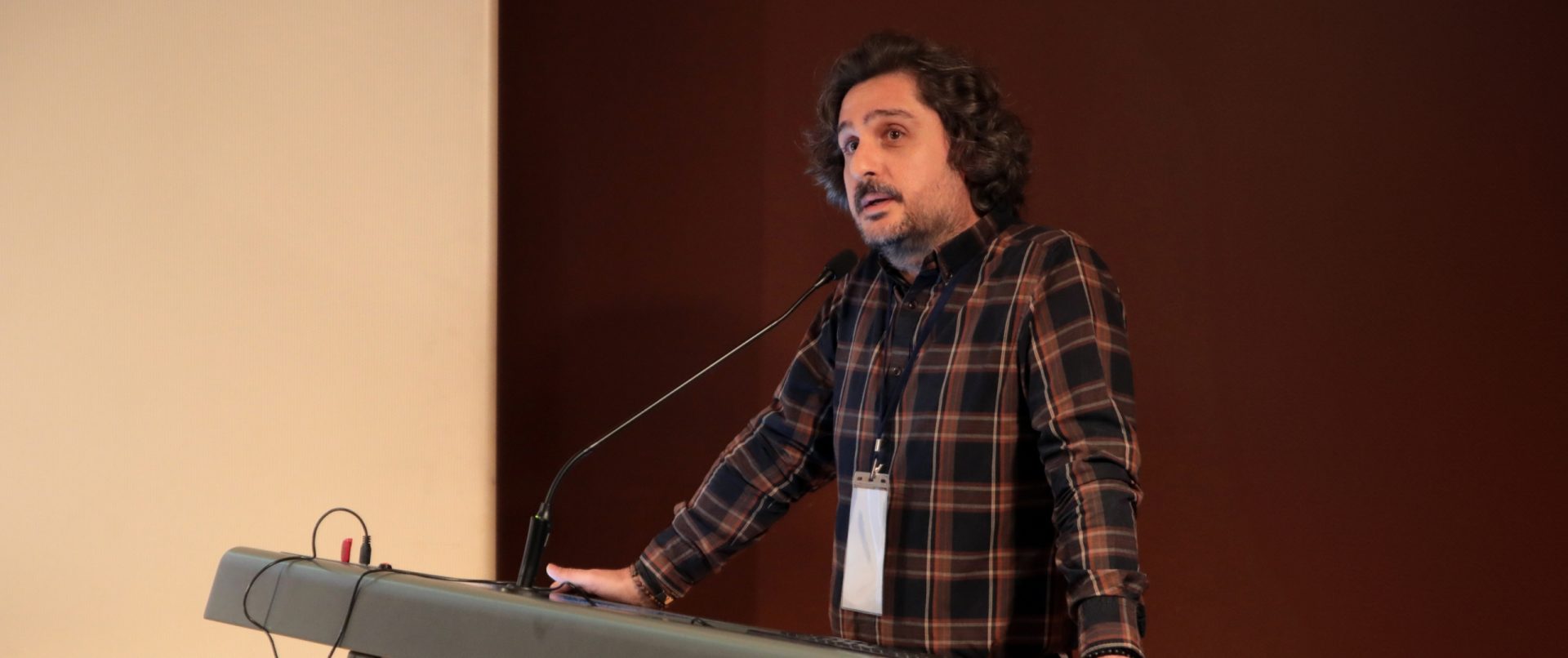 Orhan Erkut, bir kürsüde konuşma yaparken (yakın plan).